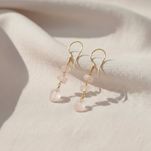 Gold earrings with pink stones on a light gray background