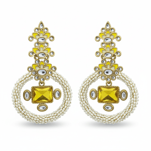 A pair of ornate gold-toned dangle earrings with bright yellow enamel, clear rhinestone embellishments, and circular strands of small white beads, displayed on a solid green background.