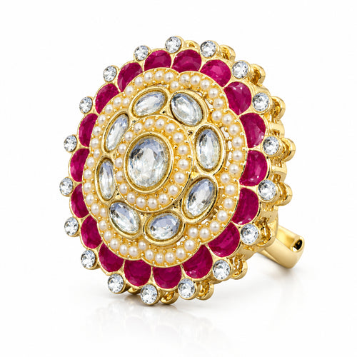 A gold-plated mandarin ring featuring bright pink enamel, white faux pearls, and clear stones, set against a solid purple background.