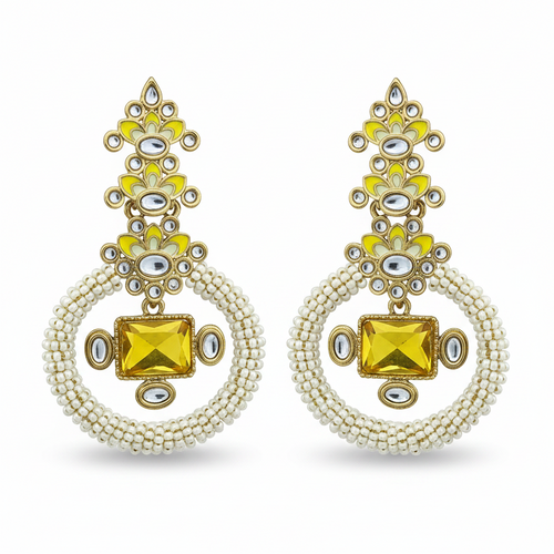 A pair of ornate gold-toned dangle earrings with bright yellow enamel, clear rhinestone embellishments, and circular strands of small white beads, displayed on a solid green background.